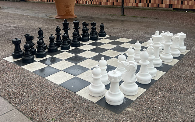Ett stort schackbräde målat på marken med stora spelpjäser.