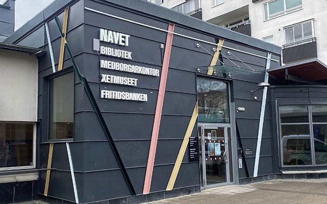 Entrén till en byggnad klädd i mörkgrå plåt.